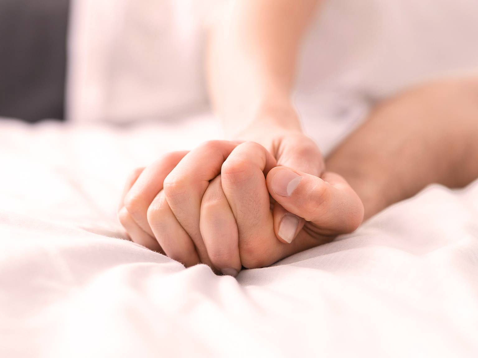 Paar liegt im Bett und hält Händchen