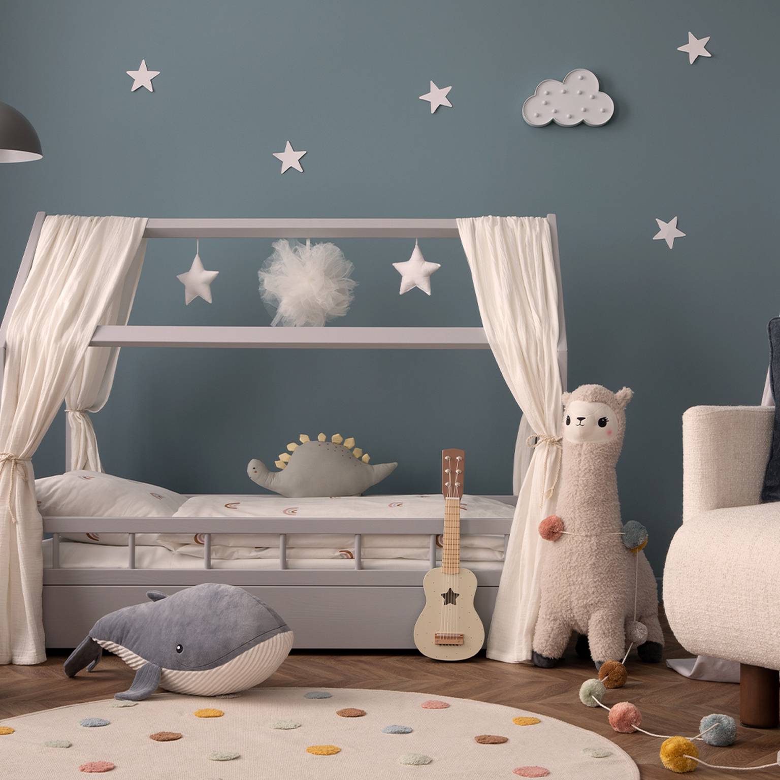 Gemütliches Kinderzimmer mit einem Bett, Sternendekoration, Plüschtieren, einer Gitarre und einem weichen Teppich auf Holzboden; die Wände sind blau mit Wolken- und Sternendekor.