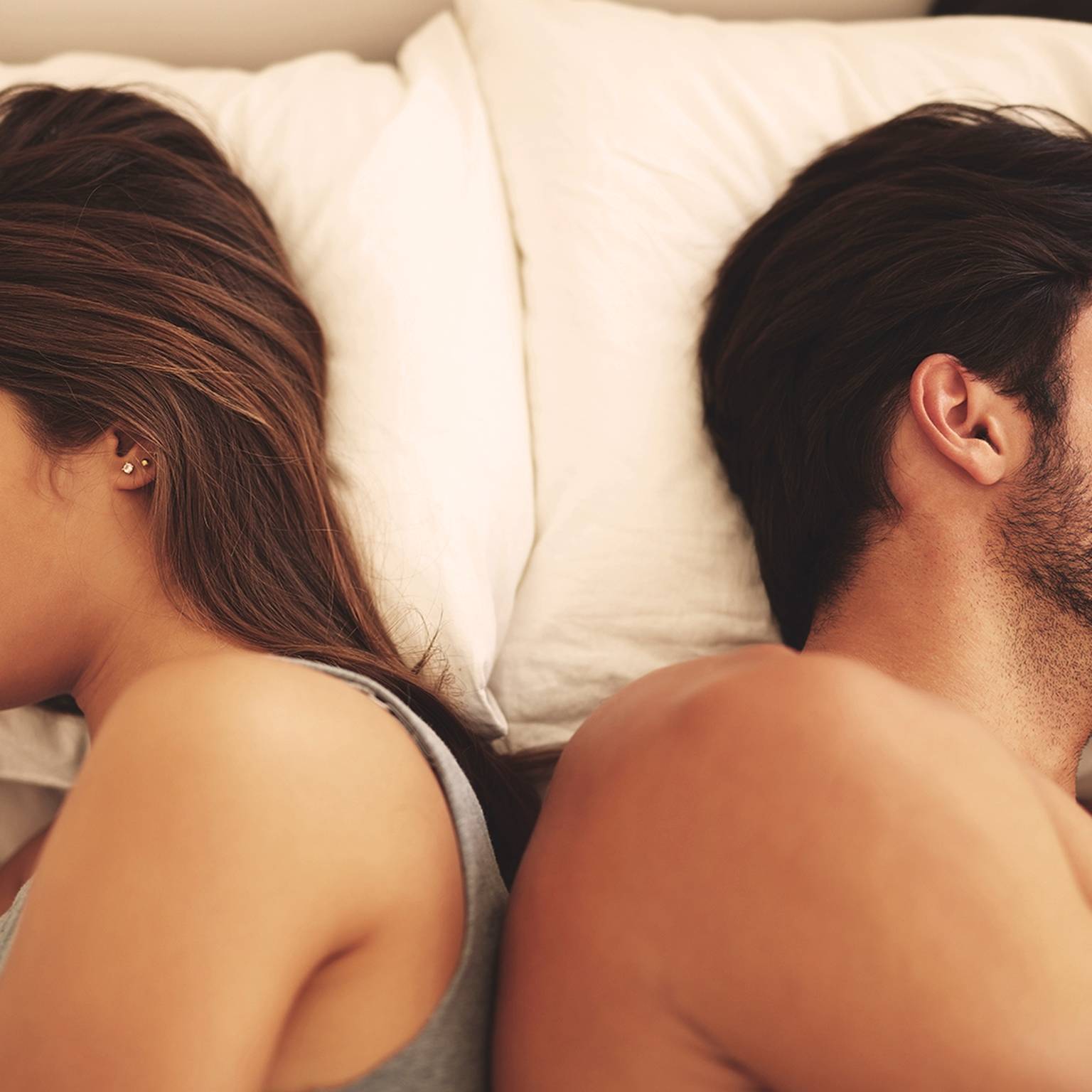EIn Paar liegt Rücken am Rücken im Bett