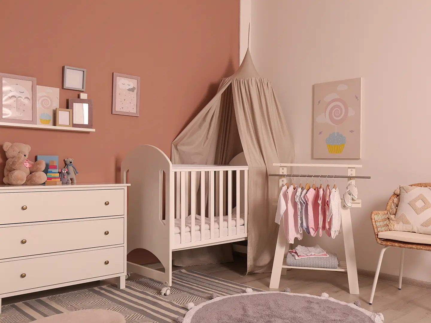 Gemütliches Kinderzimmer mit weißem Kinderbett, Baldachin, Kommode und Kleiderständer. Zur Dekoration gehören Wandkunst, Stofftiere und ein weicher Teppich.