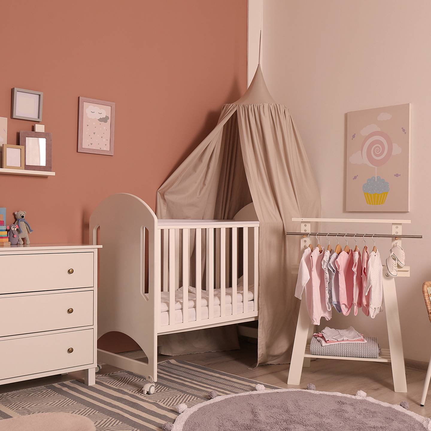 Gemütliches Kinderzimmer mit weißem Kinderbett, Baldachin, Kommode und Kleiderständer. Zur Dekoration gehören Wandkunst, Stofftiere und ein weicher Teppich.