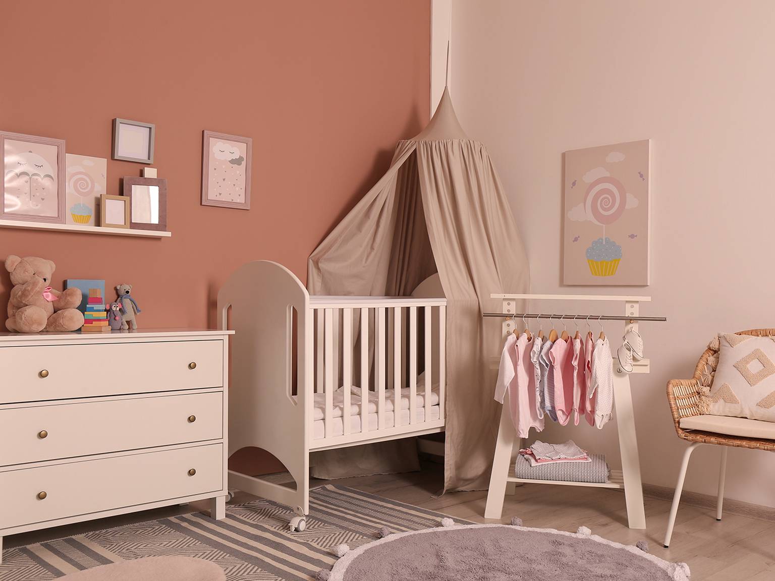 Gemütliches Kinderzimmer mit weißem Kinderbett, Baldachin, Kommode und Kleiderständer. Zur Dekoration gehören Wandkunst, Stofftiere und ein weicher Teppich.