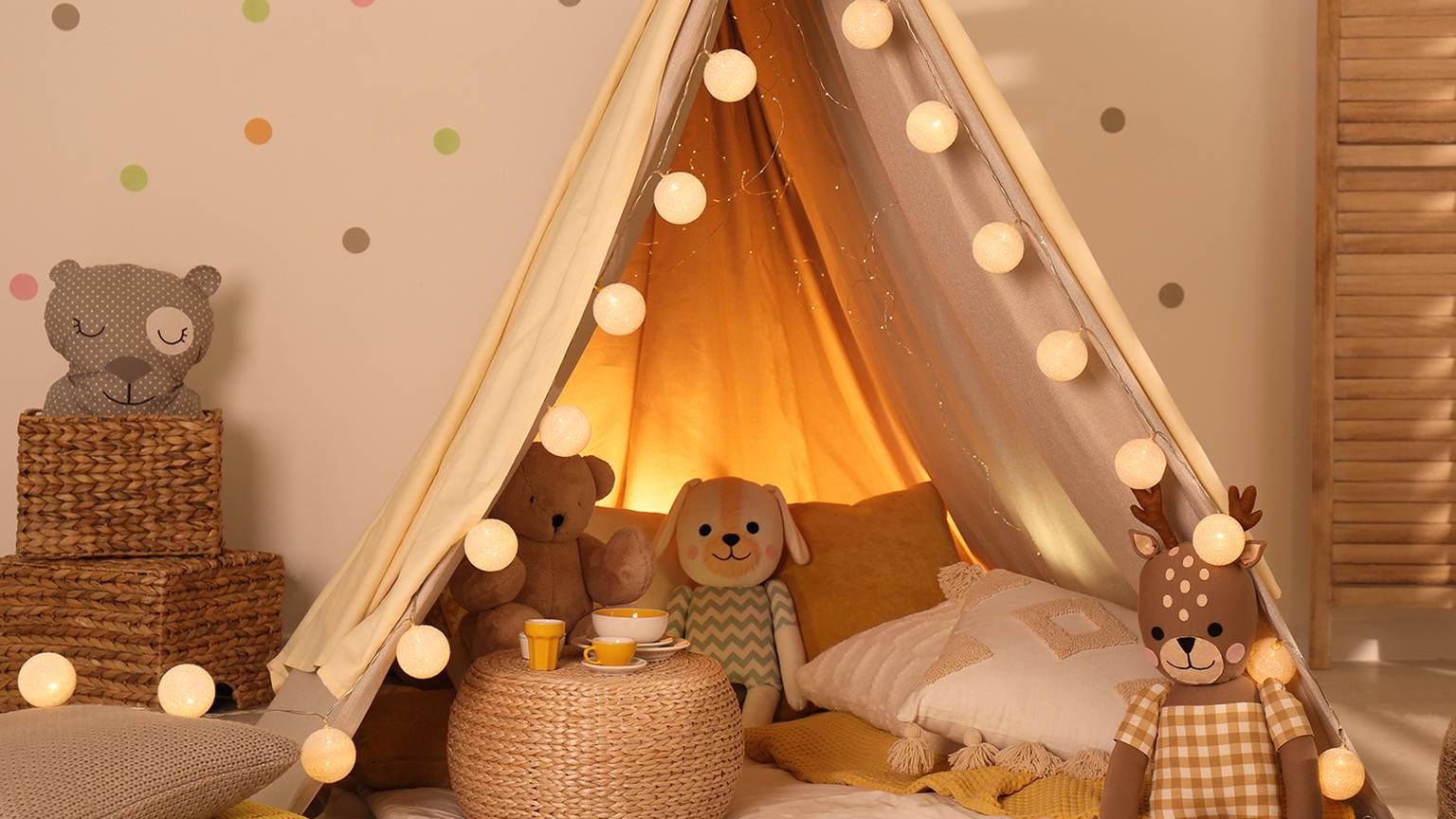 Kinderspielzelt mit Lichterketten, umgeben von Stofftieren und Kissen, die eine gemütliche und einladende Atmosphäre schaffen.