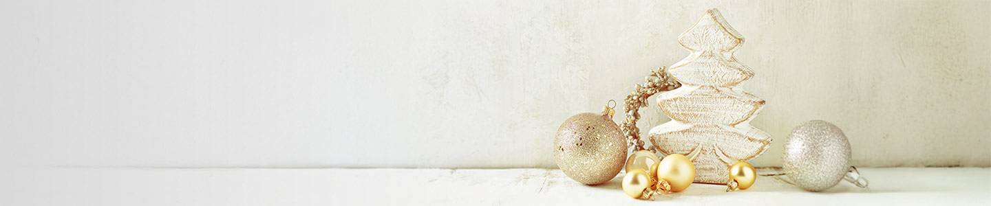 Hölzerner Weihnachtsbaum mit goldenem und silbernem Schmuck auf hellem Hintergrund.