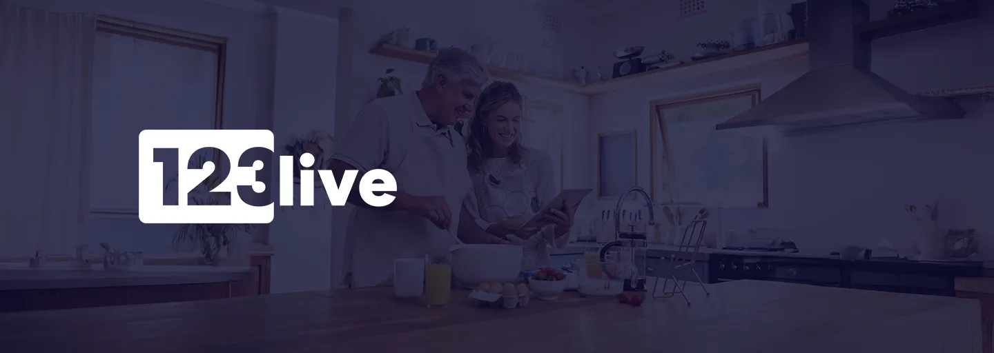 Ein Paar in einer Küche, das lächelt und auf ein Tablet schaut, mit dem Logo „123 live“ über dem Bild.