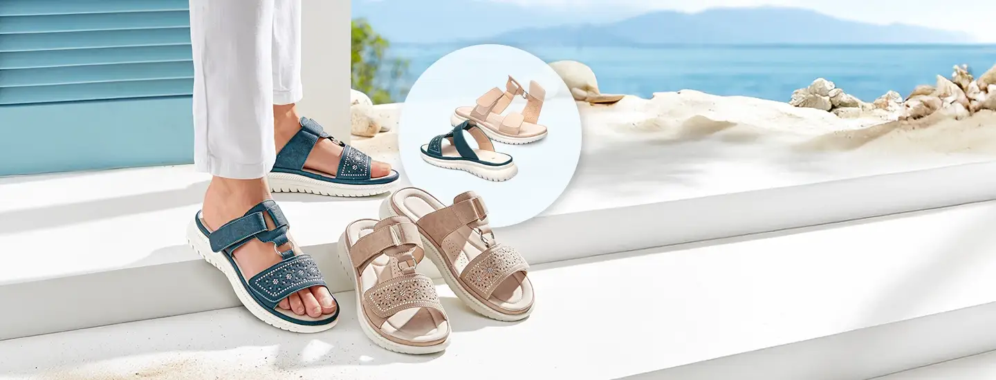 Blaue und beige Sandalen mit Riemchen und Verzierungen auf einer weißen Stufe, im Hintergrund der Blick auf das Meer und eine Nahaufnahme beider Modelle.