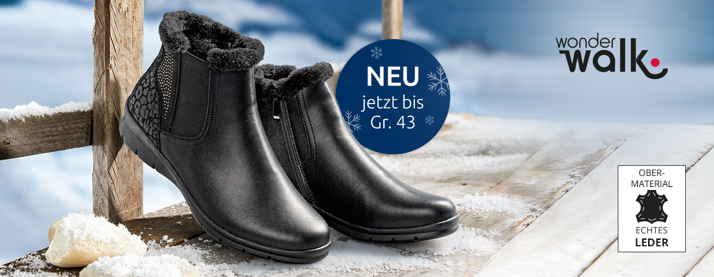 Schwarze, mit Fell gefütterte Winter-Stiefeletten auf einer verschneiten Holzfläche mit „Wonderwalk“-Logo und Leder-Materialetikett. Erhältlich bis Größe 43.