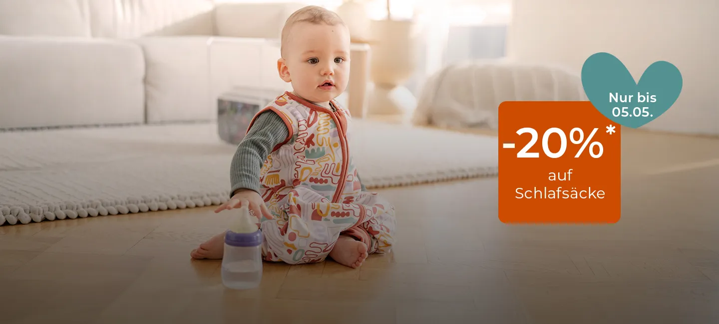 Ein Baby in einem gemusterten Schlafanzug hält eine Flasche auf dem Boden. Auf Schlafsäcke wird 20 %* Rabatt angeboten. Angebot gültig bis zum 5. Mai.