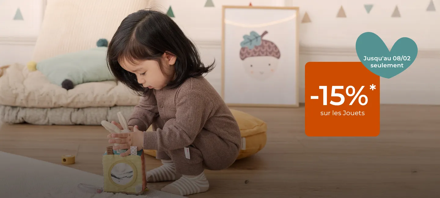 Un tout-petit joue avec un bloc de construction dans une chambre confortable. (Texte offre une réduction de 15 % sur les jouets jusqu'au 8 février.)