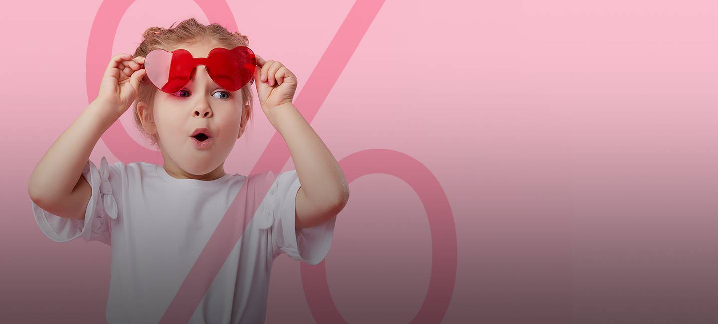 Junges Mädchen mit roter herzförmiger Sonnenbrille, das vor einem rosa Hintergrund mit einem großen Prozentsymbol überrascht aussieht.