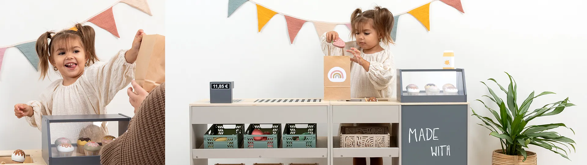 Ein kleines Kind spielt Kaufladen und packt Spielzeug-Donuts in eine Papiertüte. Eine kleine Kasse zeigt einen Preis an, und bunte Wimpelketten schmücken die Wand.