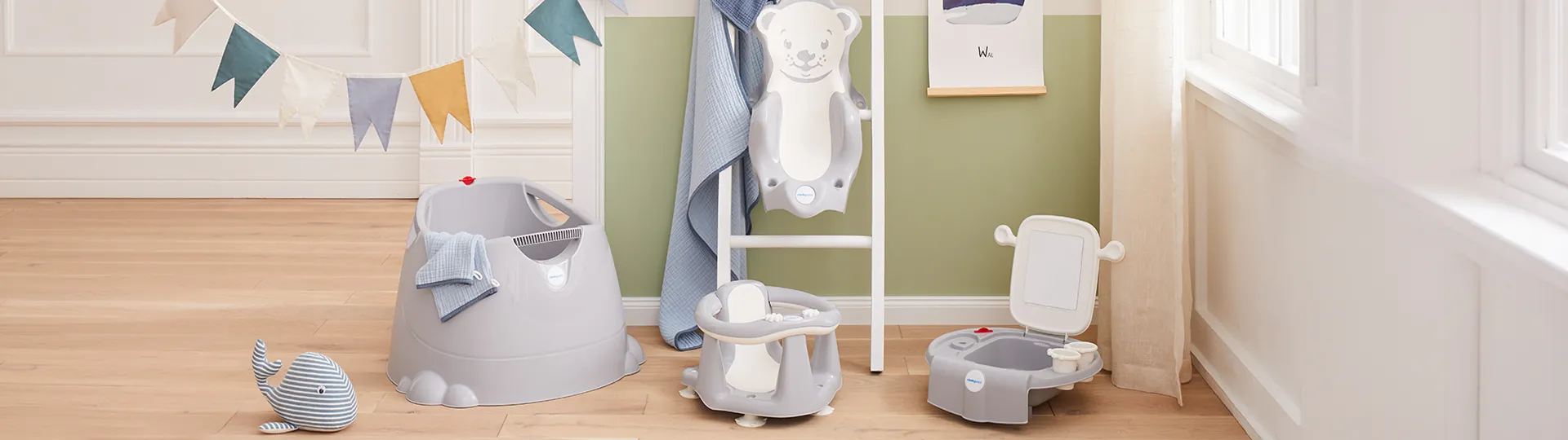 Kinderbadezimmer mit Badewanne, Stuhl und Toilette in einem hellen Raum. Dekorative Wimpelkette und ein Spielzeugwal auf dem Holzboden.