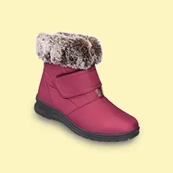 Ein roter Winterstiefel mit Kunstfellbesatz, Klettverschluss und schwarzer Sohle vor einem hellgelben Hintergrund.