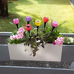 Bepflanzter Balkonkasten mit bunten Blumen und dekorativen Tulpen-Steckern, frische Balkon- und Gartendekoration für den Außenbereich.