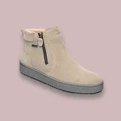 Beigefarbene Wildleder-Stiefeletten mit seitlichem Reißverschluss und grauer, strukturierter Sohle, präsentiert vor einem einfarbigen rosa Hintergrund.