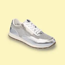 Silberner Sneaker in Metallic-Optik mit weißen Schnürsenkeln und Mesh-Struktur auf hellgelbem Hintergrund.
