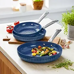 Blaue Bratpfannen mit Edelstahlgriffen auf heller Küchenarbeitsplatte, ideal für gesundes Braten, modernes Kochgeschirr für die Küche.