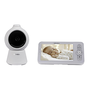 Beaba Babyphone-Set mit Kamera, Monitor und Smartphone-App auf einer weißen Kommode. Auf dem Monitor und dem Smartphone ist die Live-Ansicht eines schlafenden Babys zu sehen. Die weiße Kamera steht zentral im Vordergrund, während im Hintergrund ein dekoratives Kissen in Blumenform und weitere Wohnaccessoires zu sehen sind.