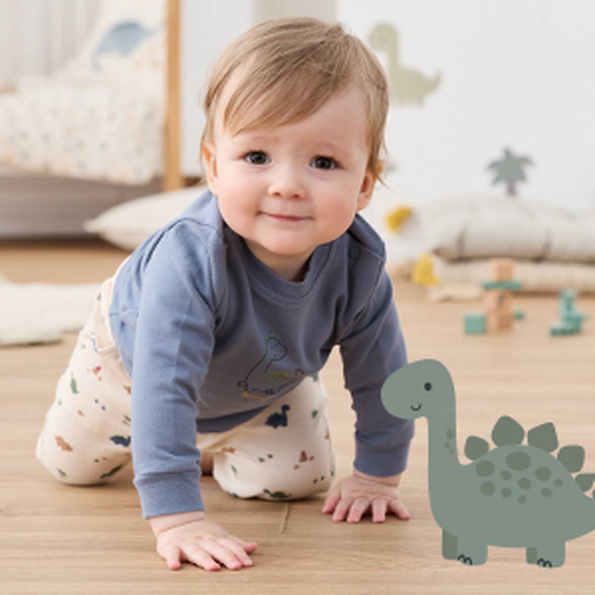 Ein Baby in einem blauen Hemd und einer gemusterten Hose krabbelt auf einem Holzboden in einem Kinderzimmer, mit einem Spielzeugdinosaurier neben sich.