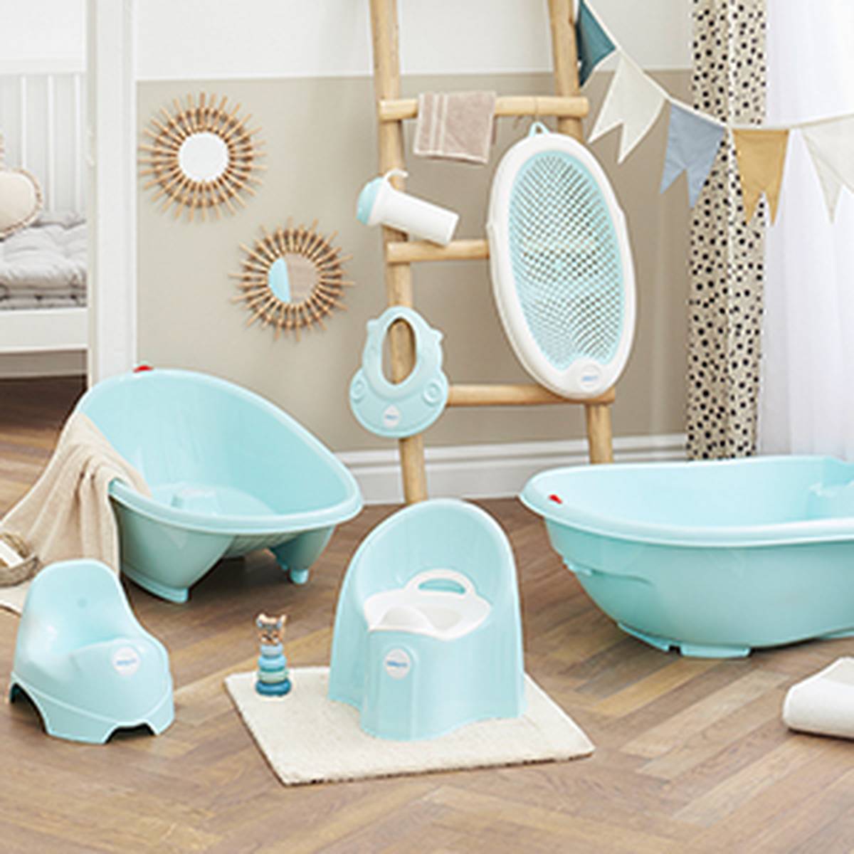 Ein Kinderzimmer mit blauen Babybadeartikeln, darunter Badewannen, Töpfchen und Stuhl. Eine Holzleiter mit Dekor und ein gemütlicher Teppich auf einem Holzboden.