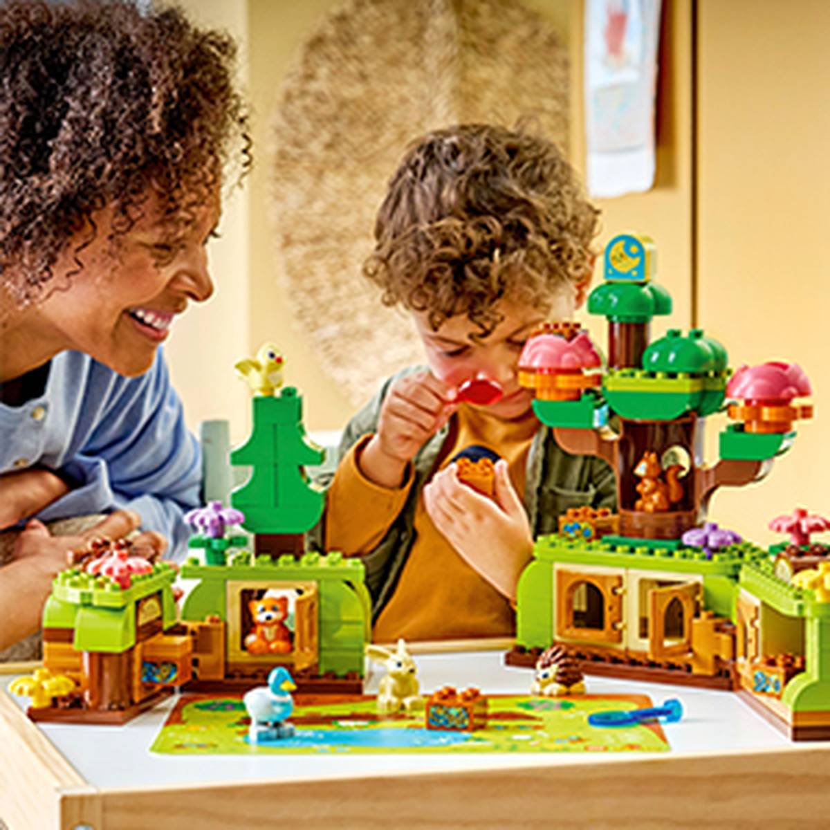 Ein Kind und ein Erwachsener spielen mit einem bunten, Lego-ähnlichen Spielzeugset, das Bäume und Tiere enthält, und gehen dabei einer unterhaltsamen und fantasievollen Beschäftigung nach.