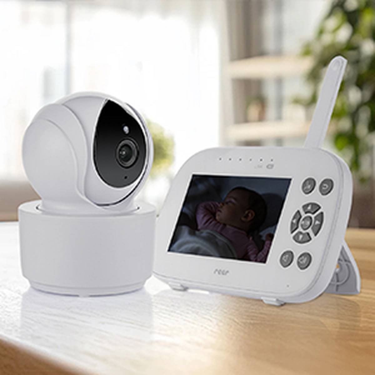 Ein Babyfon-Set mit einer Kamera und einem Bildschirm, der ein schlafendes Baby zeigt. Die Geräte stehen auf einer Holzoberfläche in einem sanft beleuchteten Raum.
