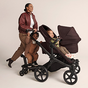 Bugaboo Donkey 6 Kinderwagen mit großem Verdeck und Mitfahrbrett für ein weiteres Kind. Der Kinderwagen wird zusammen mit zwei Kindern in einer Studioaufnahme auf hellem Hintergrund gezeigt.