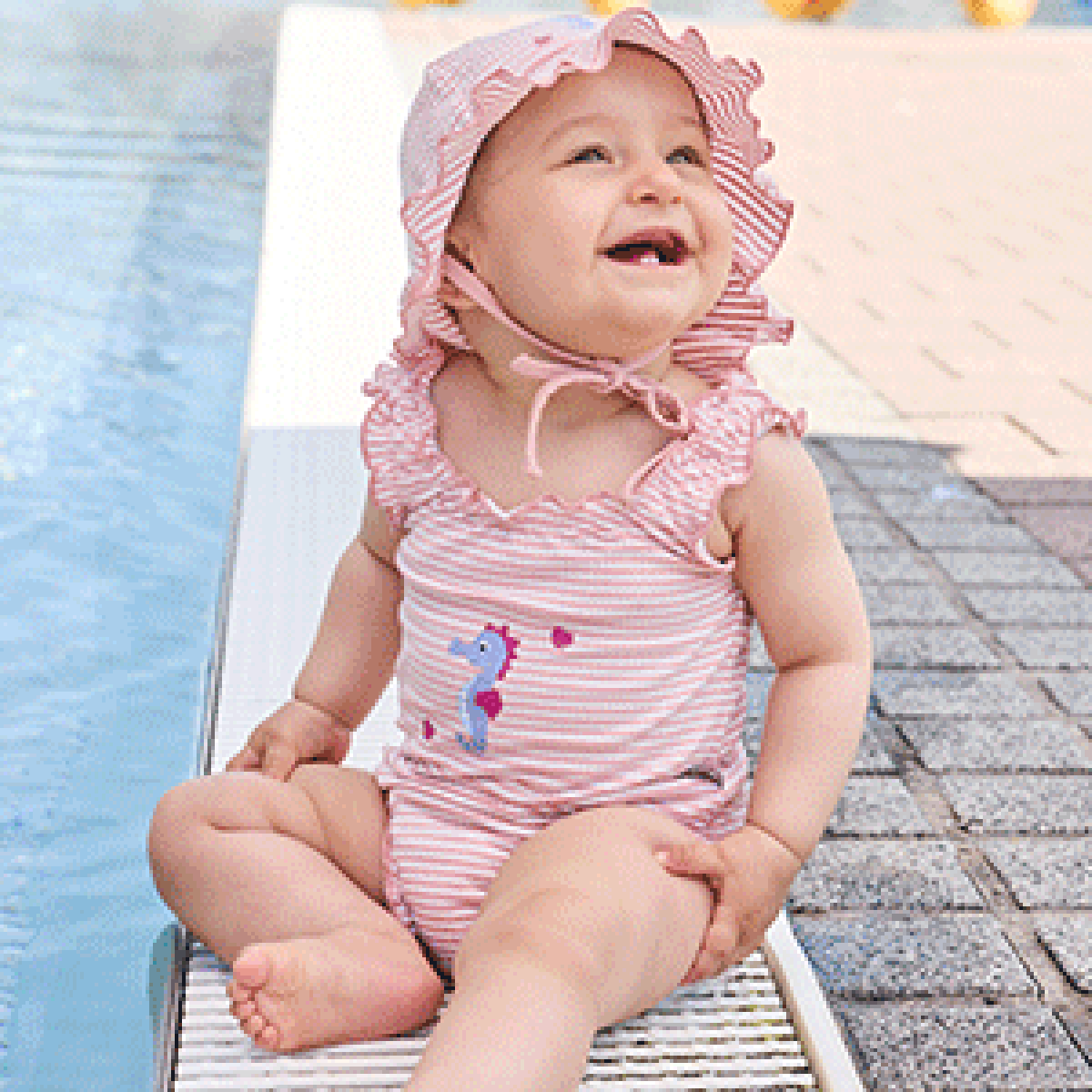 Plantschende Babys am Wasser, in Sterntaler Badeklamotten und passenden Hüten.