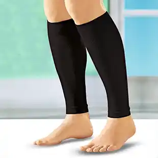 Person mit schwarzen Kompressionsstrümpfen an den Waden, die barfuß auf einer glatten, hellen Oberfläche steht.