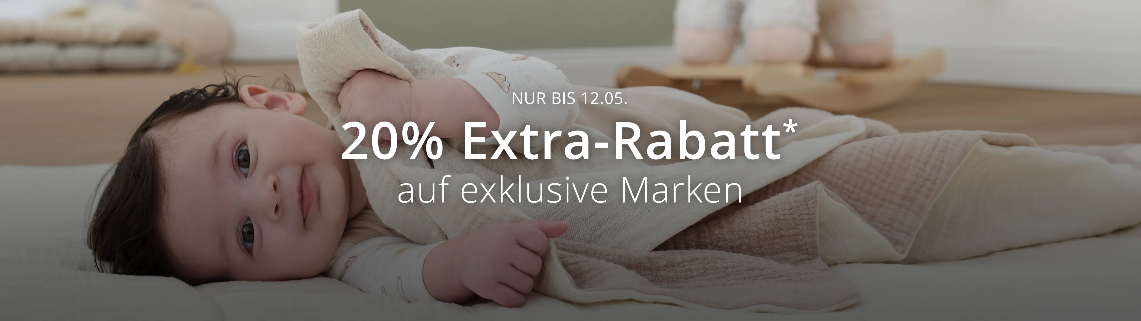 Baby liegt auf einer weichen Decke, darüber ein Text-Overlay mit dem Hinweis auf 20% Extra-Rabatt* auf exklusive Marken