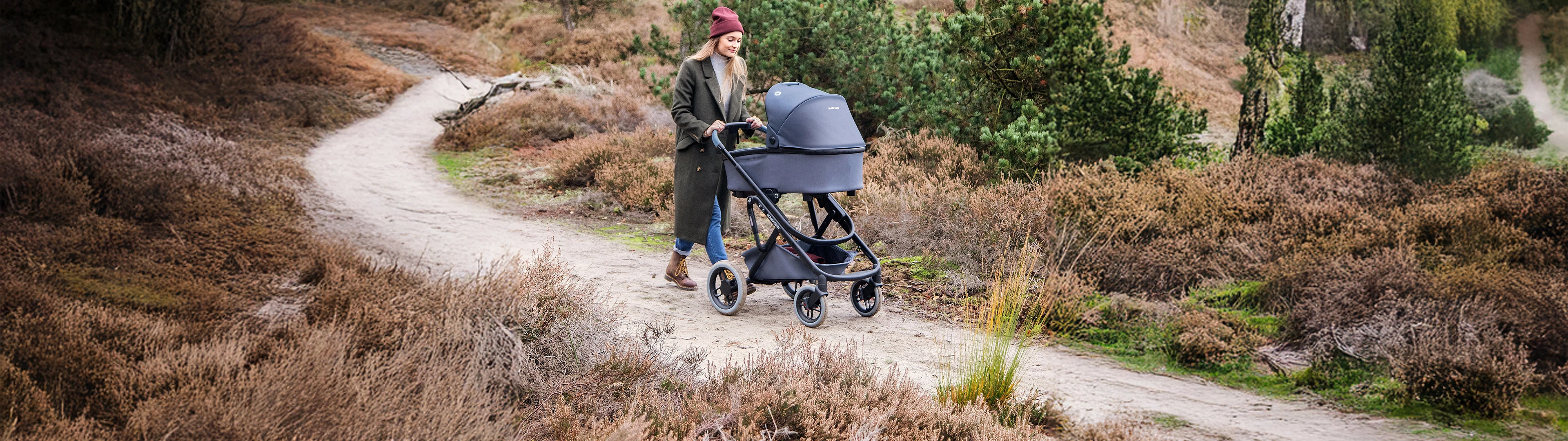 Eine Frau schiebt einen Kinderwagen in der Natur