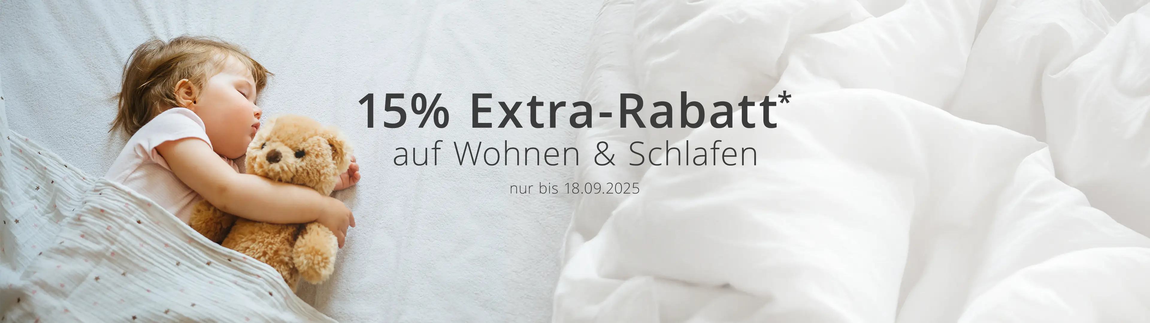 Kind schläft mit einem Teddybär auf einem weißen Bett. Text: „15 % Extra-Rabatt auf Wohnen & Schlafen, nur bis zum 18.09.2025.“