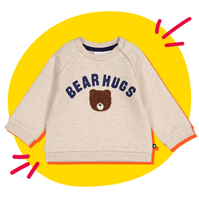 Beiges Sweatshirt für Kleinkinder mit der Aufschrift „Bear Hugs“ und einem Bärengesicht vor einem gelben Hintergrund mit roten Kritzeleien.