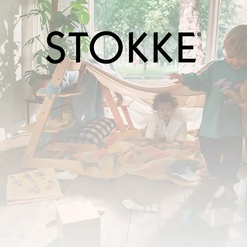 Zwei Kinder spielen drinnen mit einem hölzernen Spielzelt und Spielzeug. Natürliches Licht strömt durch große Fenster, und das Wort „STOKKE“ ist darüber eingeblendet.