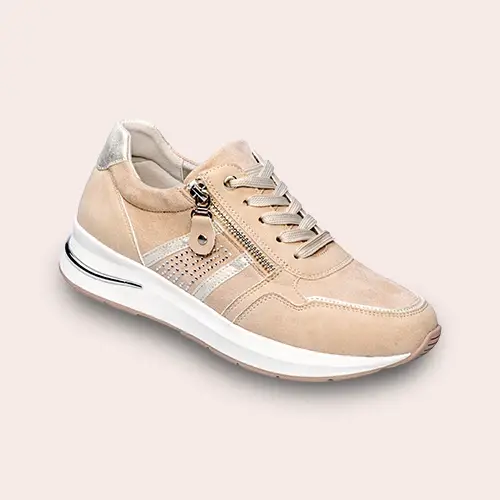 Beigefarbener Sportschuh mit weißer Sohle, silbernen Akzenten, seitlichem Reißverschluss und Schnürsenkeln auf hellem Hintergrund.