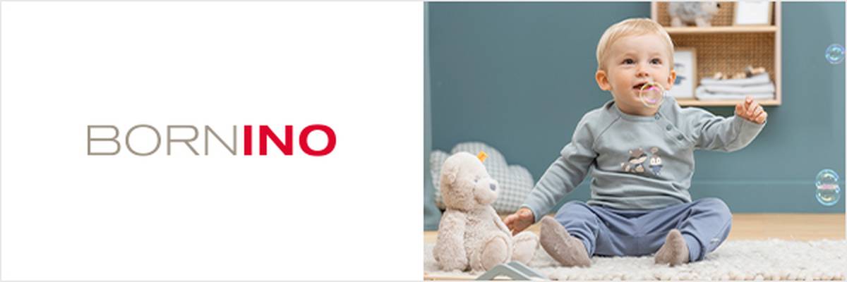 Ein Baby sitzt lächelnd auf dem Boden, umgeben von Spielzeug und Seifenblasen. Ein Plüschtier und ein kleiner roter Lastwagen stehen daneben. Links steht „BORNINO“.