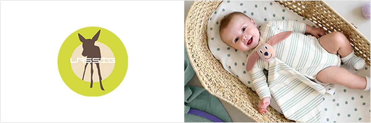 Logo eines Rehs auf einem grünen Kreis neben einem lächelnden Baby in einem gestreiften Strampler, das in einem geflochtenen Korb mit einem Plüschtier liegt.