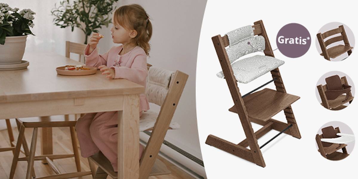 Ein Kind in einem rosa Outfit sitzt auf einem Stokke Tripp Trapp Hochstuhl und isst. Hinweis auf Gratis Sitzkissen