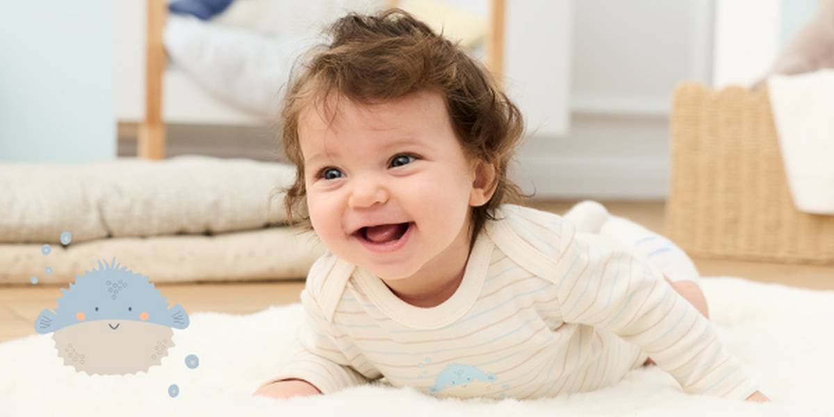 Ein lächelndes Baby in einem gestreiften Strampler auf einem weichen Teppich, daneben eine niedliche Kugelfischillustration, in einem gemütlichen, hellen Zimmer.