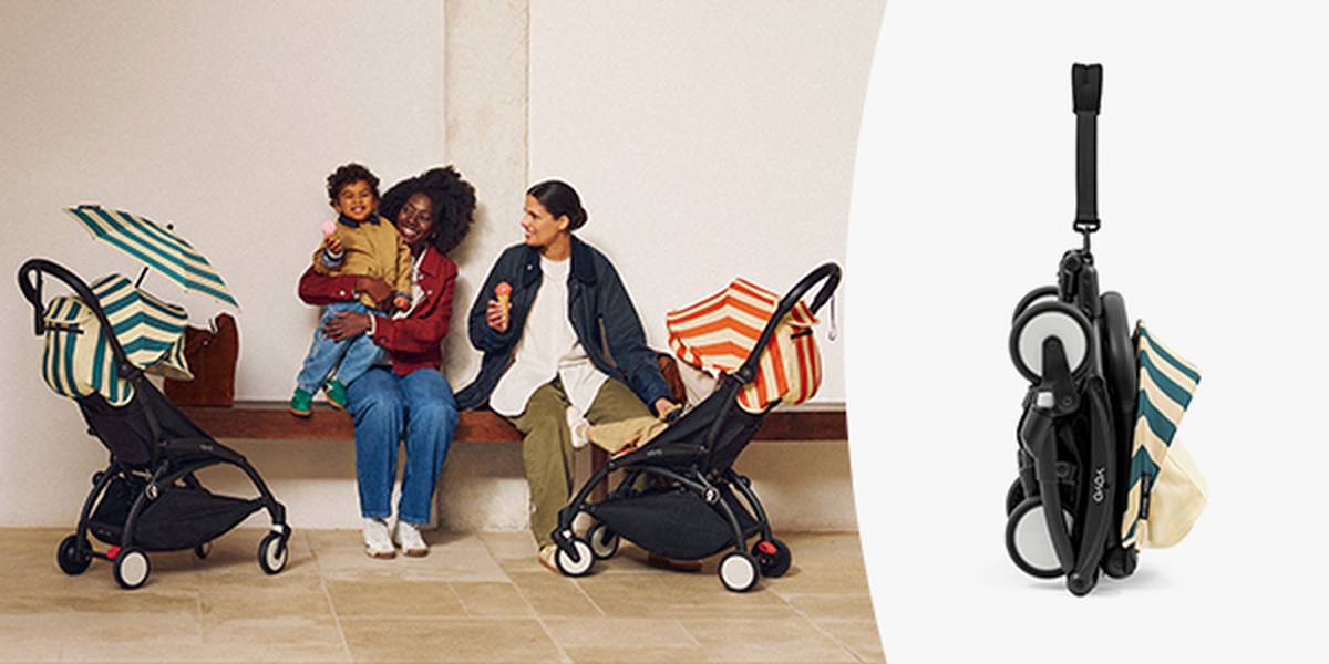 Zwei Frauen mit einem Kind sitzen auf einer Bank; jede hat einen Kinderwagen mit gestreiftem Verdeck bei sich. Rechts ist separat ein zusammengeklappter Kinderwagen zu sehen.