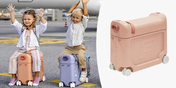 Zwei Kinder sitzen auf Kinderkoffern auf einem Flughafen und strecken freudig die Arme hoch. Rechts ist eine Nahaufnahme eines pinkfarbenen Koffers zu sehen.