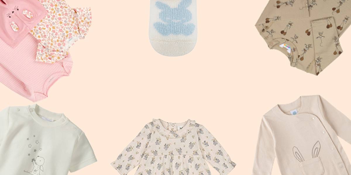 Verschiedene Babykleidung mit Hasenmotiven, darunter Blumenkleider, pastellfarbene Strampler und ein Pullover, arrangiert auf beigem Hintergrund.