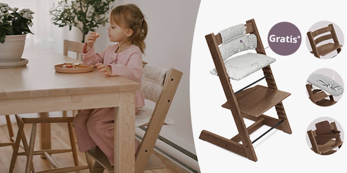 Ein Kind in einem rosa Outfit sitzt auf einem Stokke Tripp Trapp Hochstuhl und isst. Hinweis auf Gratis Sitzkissen