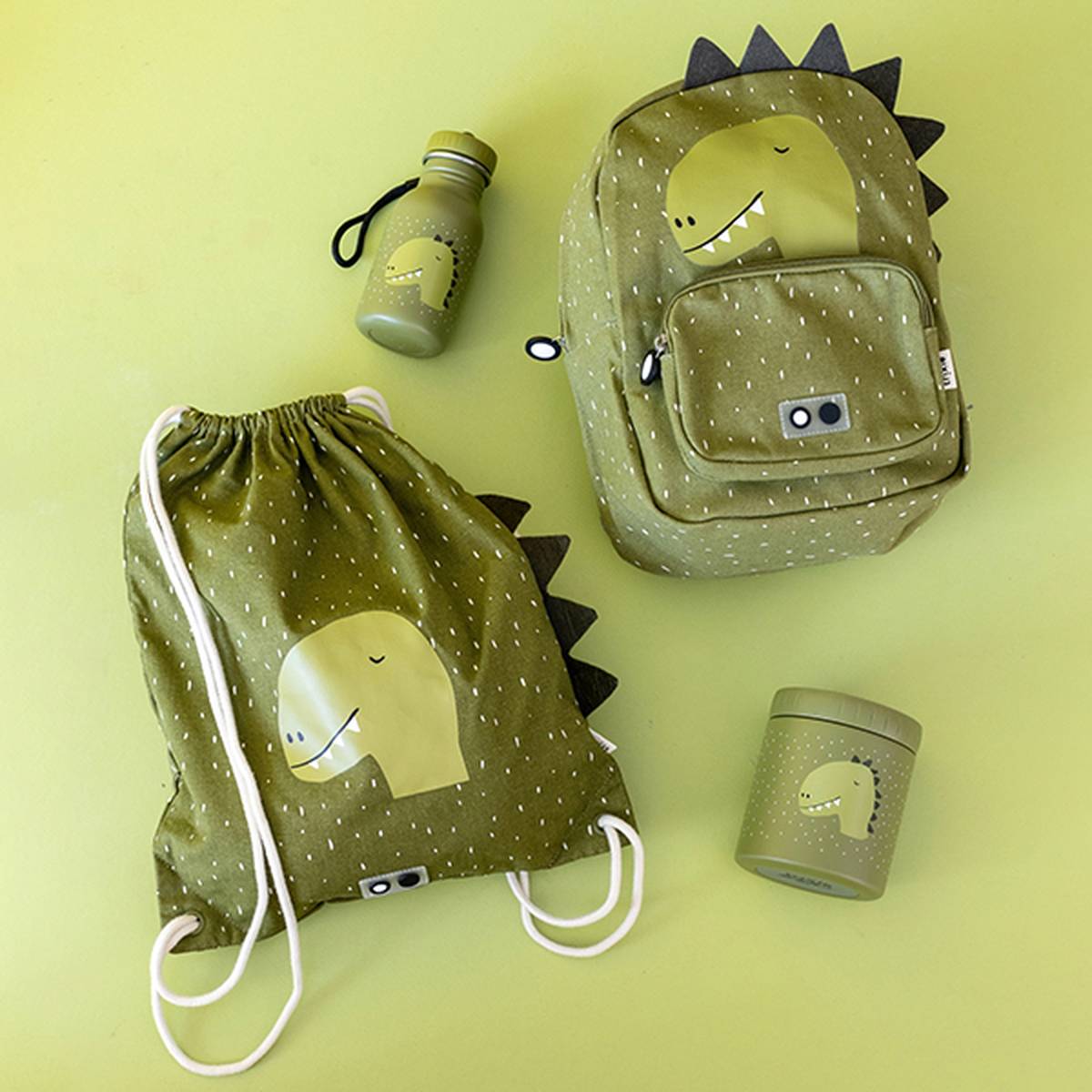 Grüner Rucksack, Turnbeutel, Wasserflasche und Behälter mit Dinosaurier-Motiven auf grünem Hintergrund. Alle Artikel sind mit einem verspielten Dinosaurier-Design versehen.