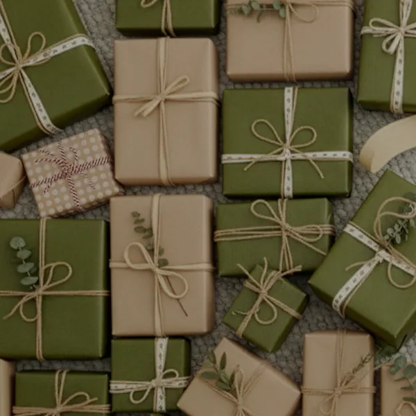 Eine Sammlung ordentlich verpackter Geschenke in grünem, beigem und gepunktetem Papier, mit Schleifen aus Kordel zusammengebunden, arrangiert auf einer strukturierten Oberfläche.