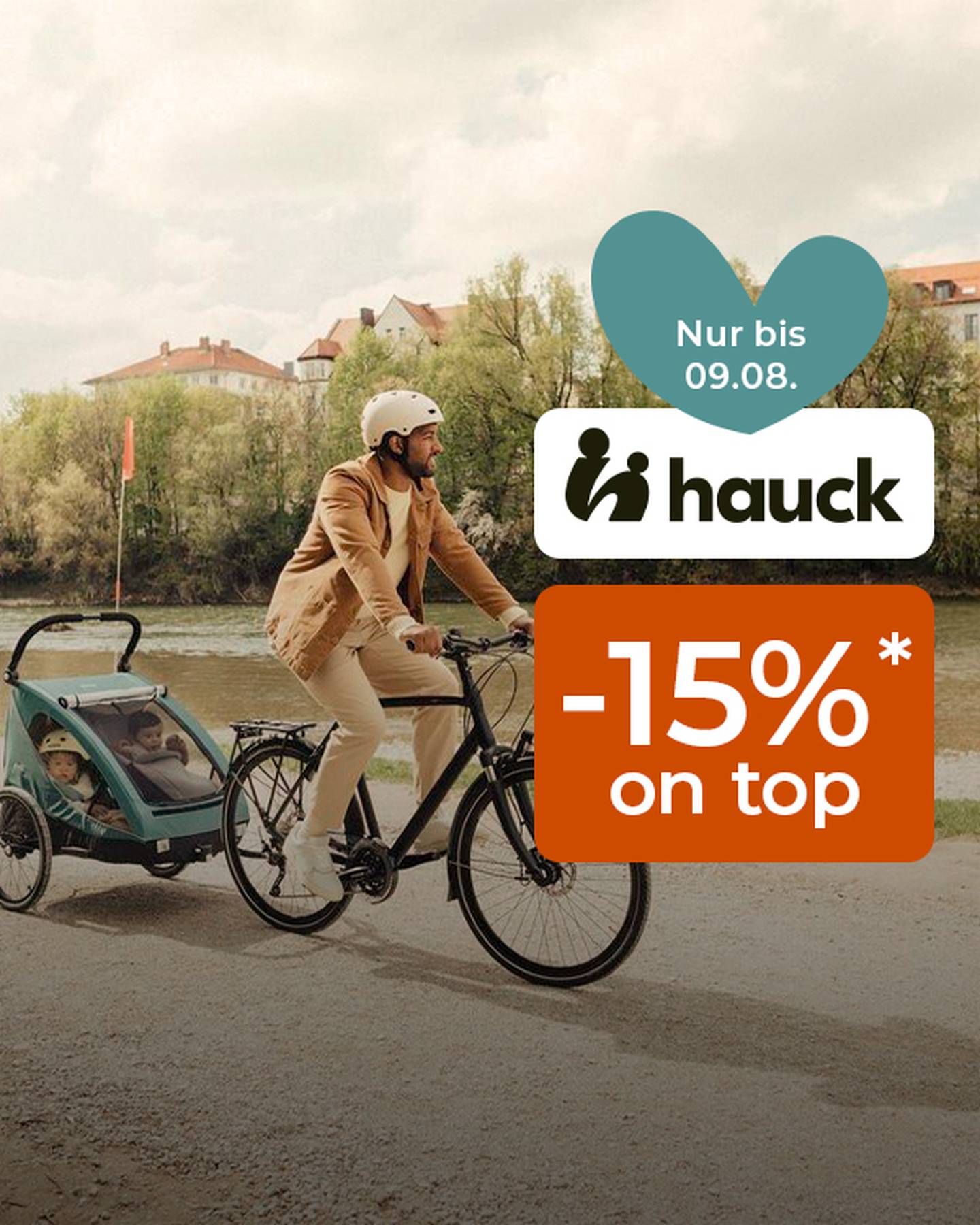 Mann fährt mit dem Fahrrad an einem Fluss entlang und zieht einen Kinderanhänger mit zwei Kindern. Ein Werbetext für ein 15%-Rabattangebot von Hauck ist eingeblendet.