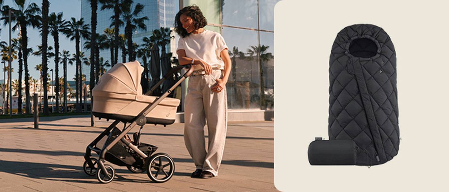 Frau schiebt beigen Kinderwagen an Palmen vorbei; rechts ist ein schwarzer, gesteppter Babyfußsack zu sehen.