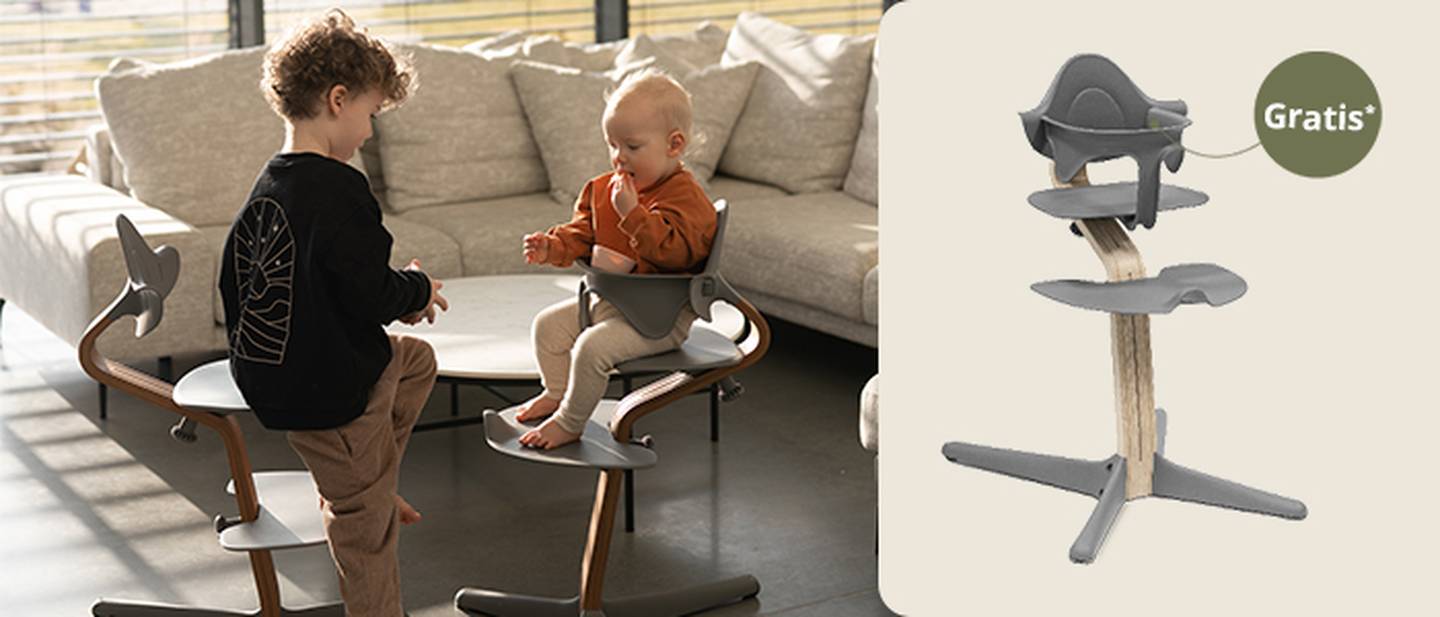 Zwei kleine Kinder sitzen auf modernen Stokke Nomi-Hochstühlen in einem sonnendurchfluteten Raum. Ein weiterer Hochstuhl ist rechts mit einem „Gratis”-Etikett zu sehen, das auf ein Babyset zeigt.
