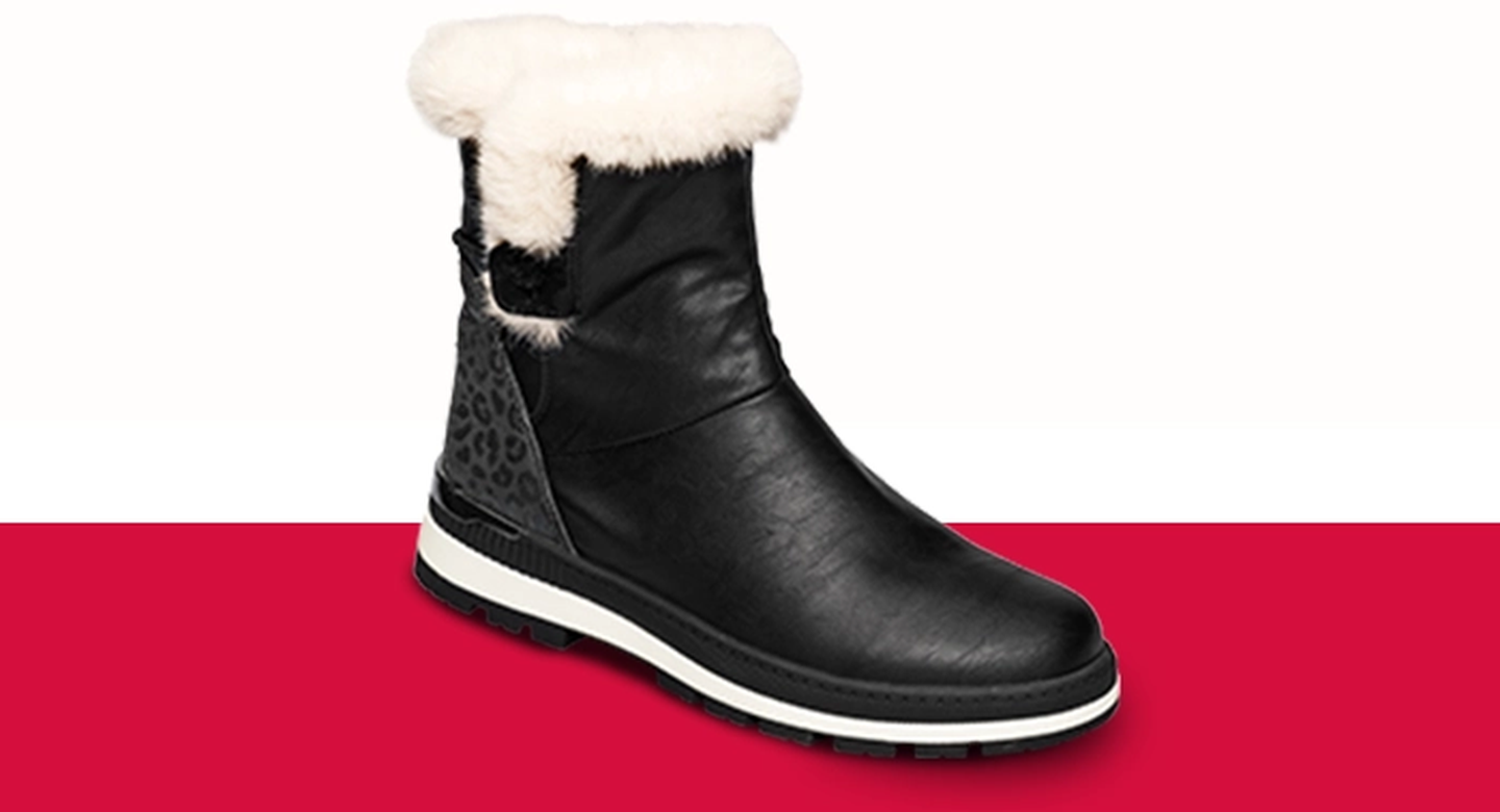 Schwarzer Winterstiefel mit weißem Kunstfellfutter, gemustertem Absatz und weißer Sohle vor rot-weißem Hintergrund.