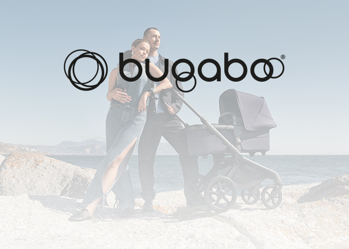 Paar steht mit einem Kinderwagen auf Felsen am Meer, Bugaboo-Logo darüber.